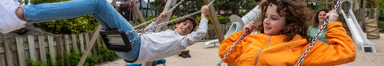 Twee kinderen aan het schommelen in de speeltuin