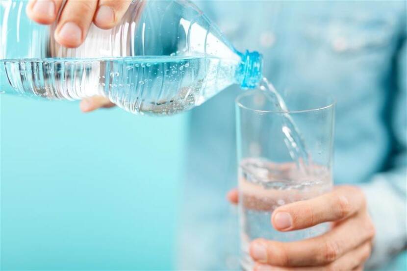 Water wordt uit een plastic fles in een glas geschonken