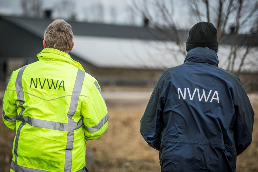 Twee inspecteurs van de NVWA kijken naar een schuur